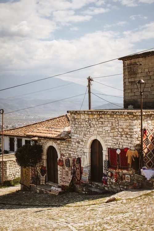 Maisons ottomanes en pierre et tapis colorés dans le quartier historique de Berat, au pied des montagnes